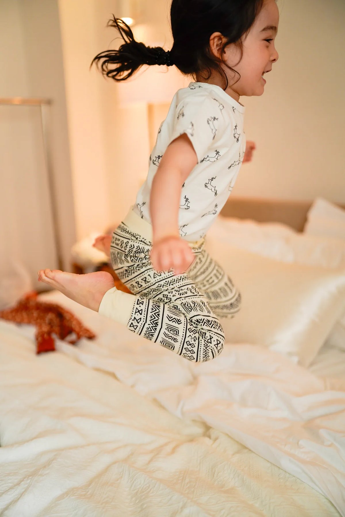 Child wearing the KendiKids Uhuru Short-Sleeved Tee — leaping gazelle print on white