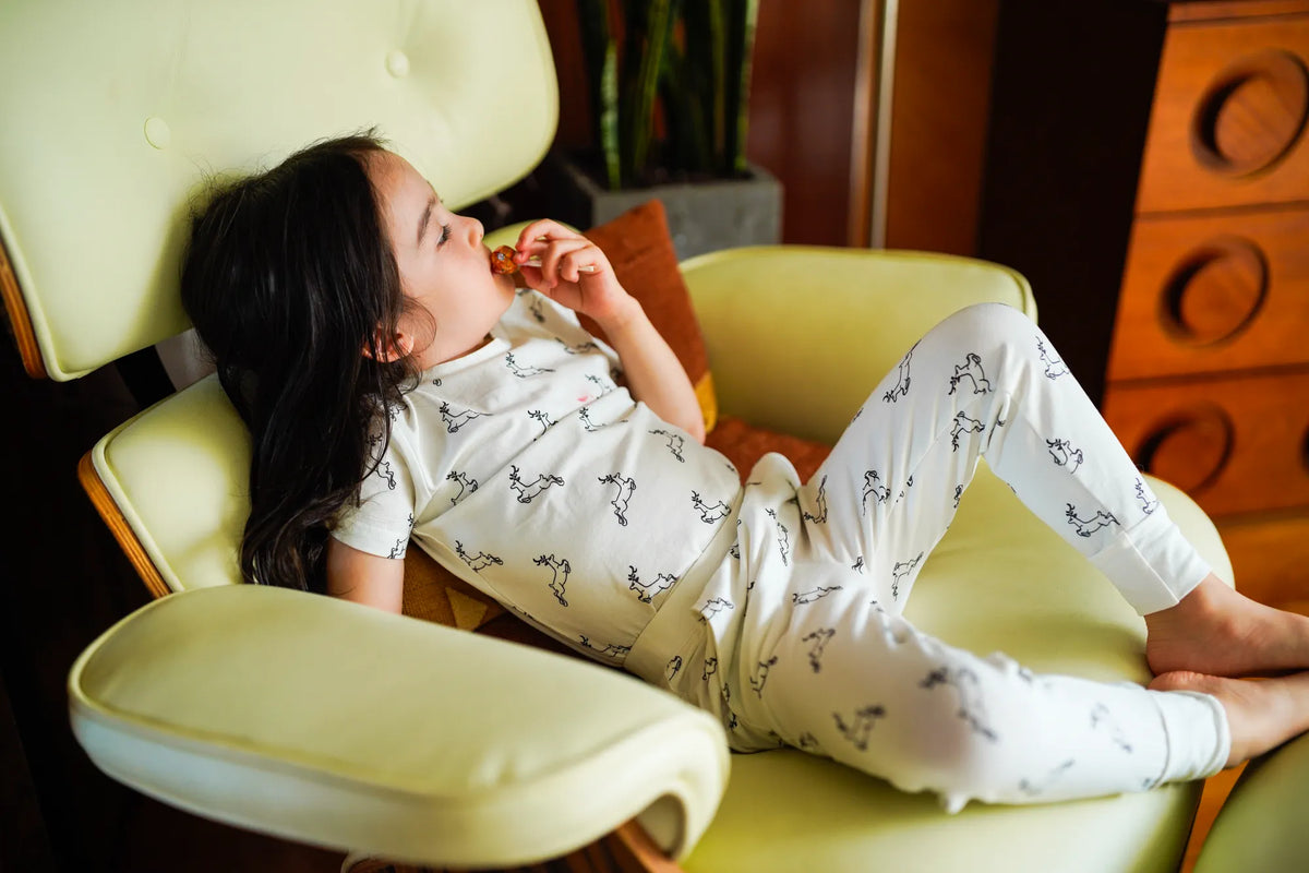 Child wearing the KendiKids Uhuru Short-Sleeved Tee — leaping gazelle print on white