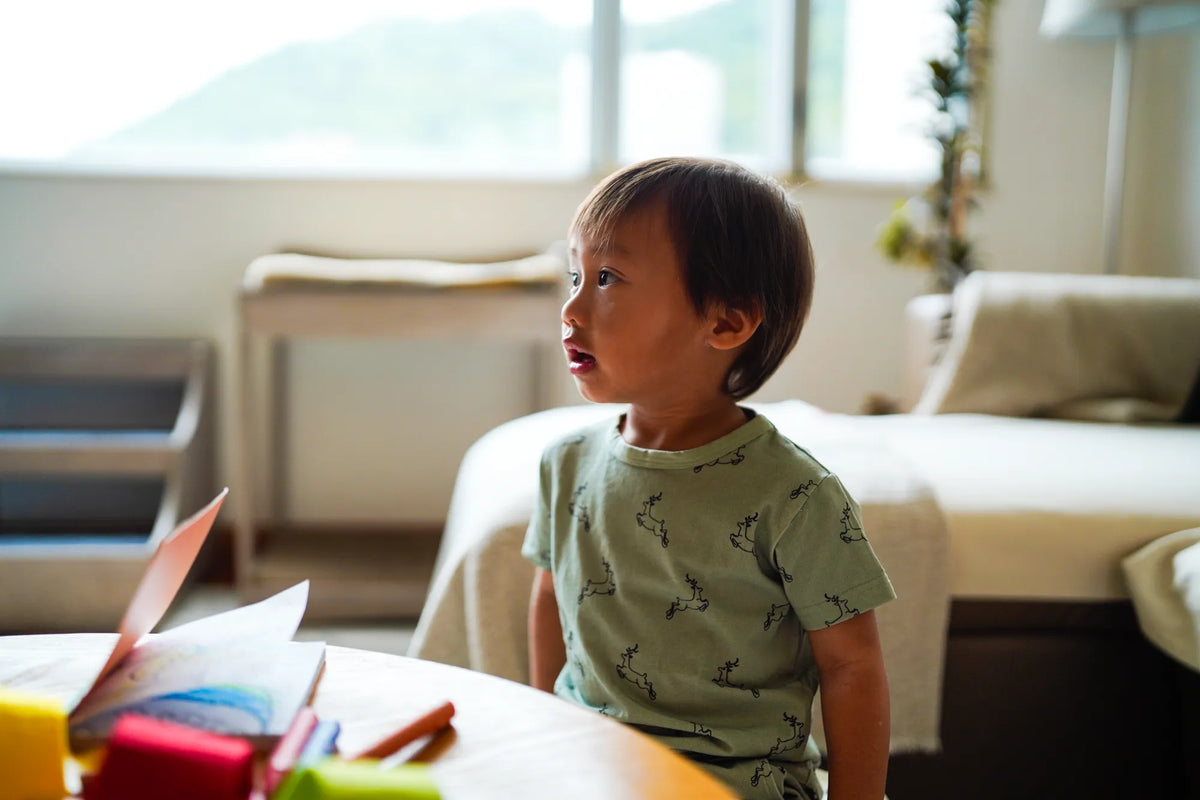 Child wearing the KendiKids Uhuru Sage Short-Sleeved Tee — leaping gazelle print on sage green