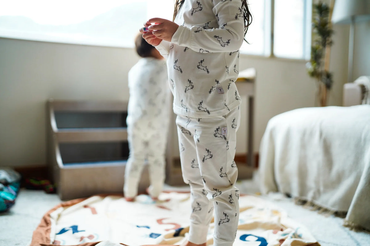 Child wearing the KendiKids Uhuru Pajama Set — leaping gazelle print on white
