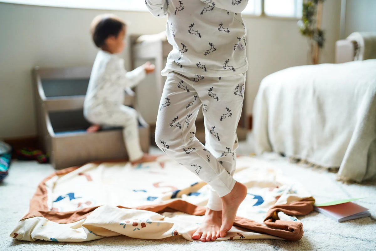 Child wearing the KendiKids Uhuru Pajama Set — leaping gazelle print on white