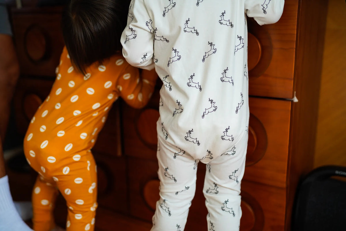 Child wearing the KendiKids Uhuru Zipper Romper — leaping gazelle print on white