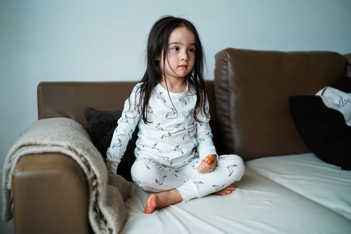 Child wearing the KendiKids Uhuru Pajama Set — leaping gazelle print on white