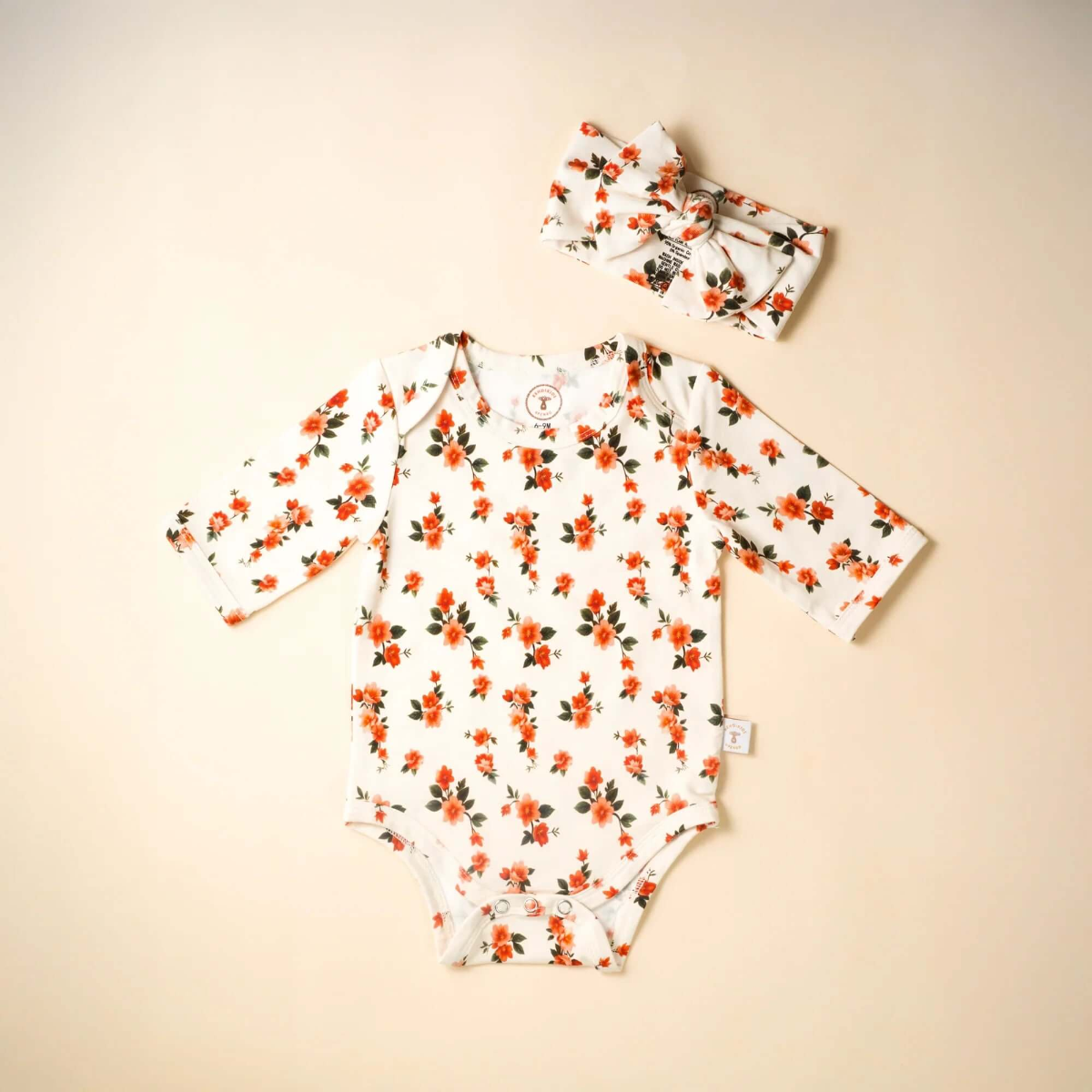 Floral baby onesie and headband on a beige background
