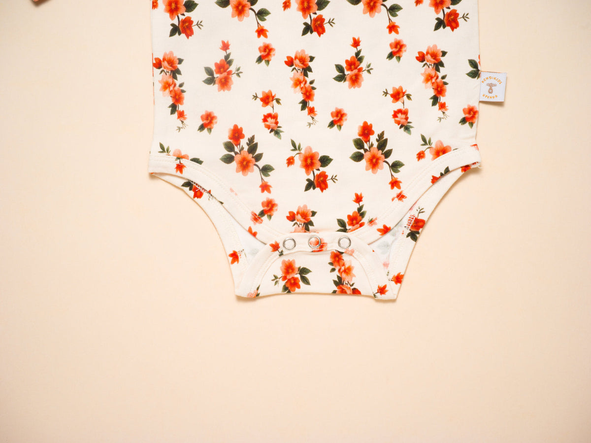 Floral-patterned baby onesie on a beige background