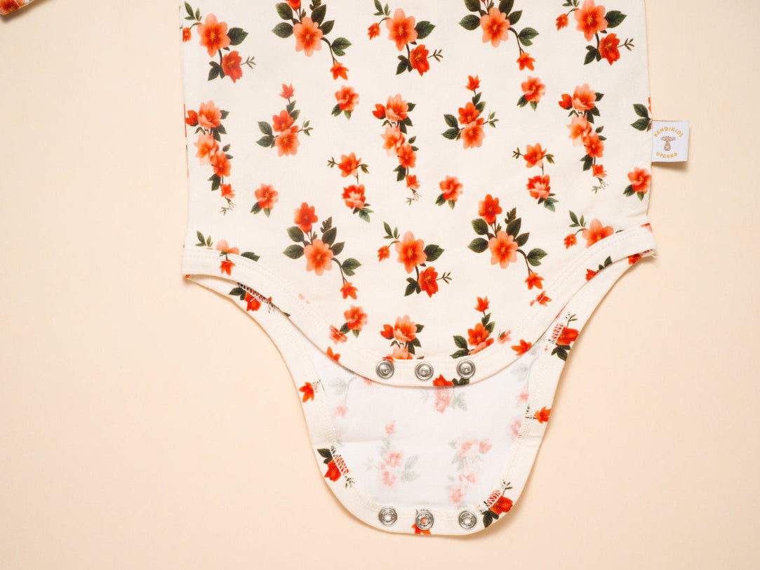 Floral-patterned baby onesie on a beige background