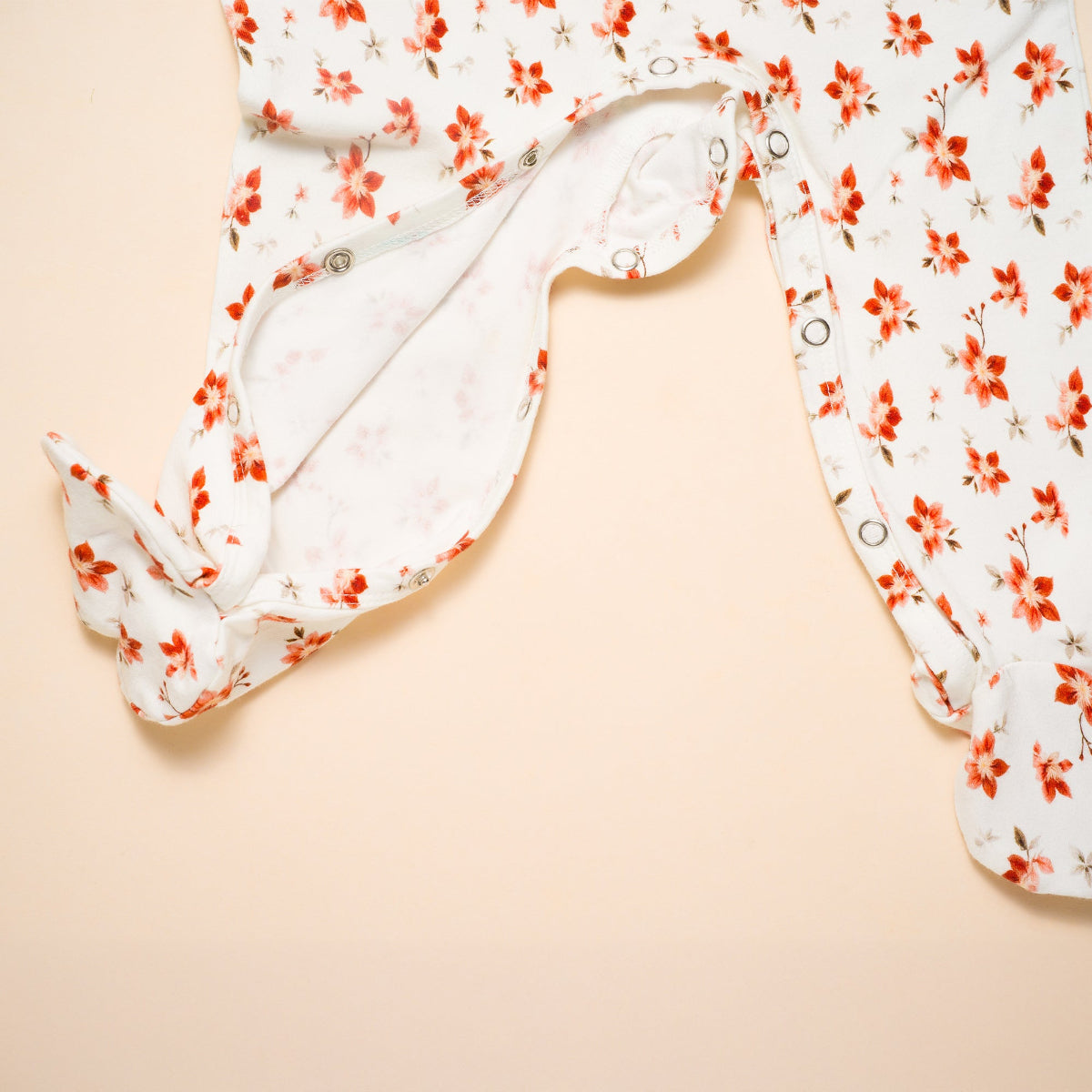 Floral-patterned baby footed romper on a beige background