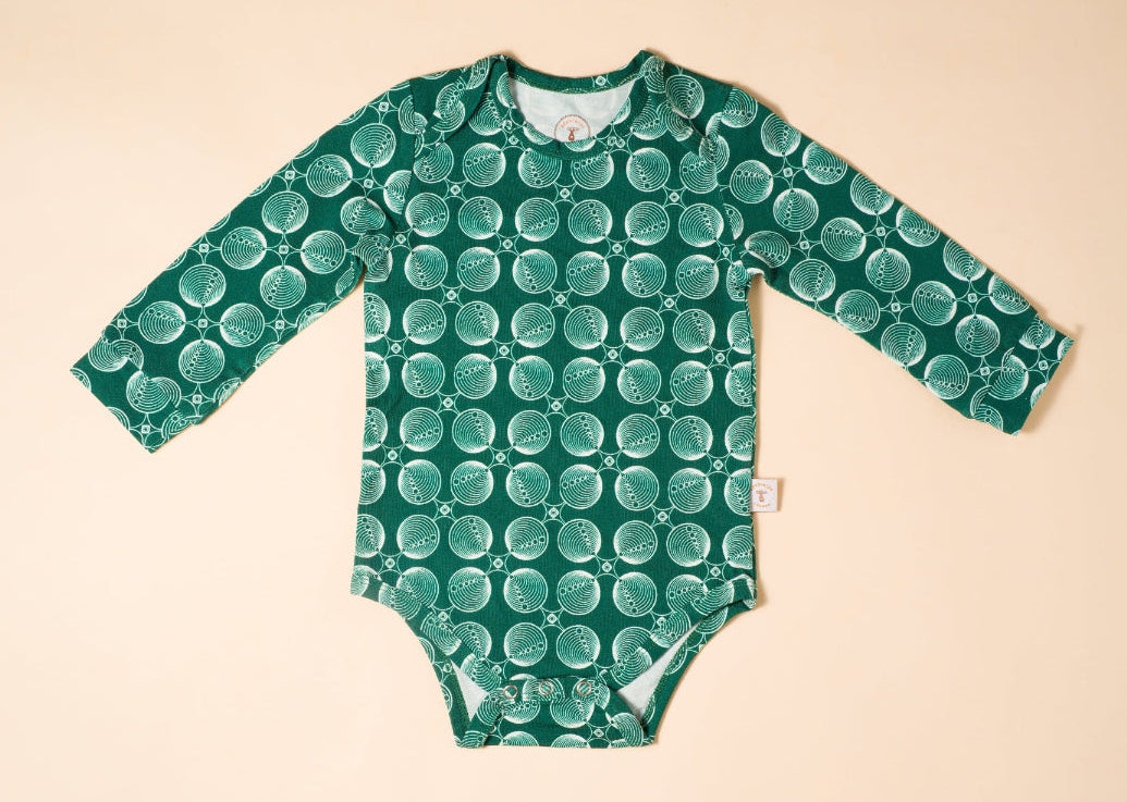 Green patterned baby onesie,bodysuit on a beige background