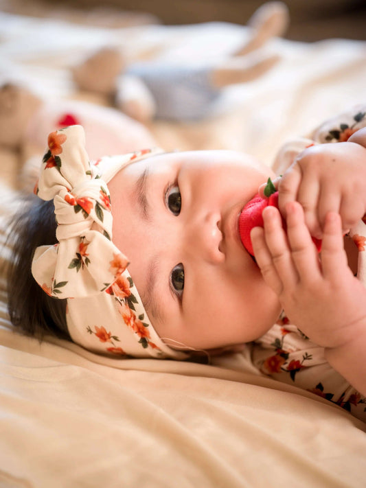 Baby lying on a bed holding a red toy