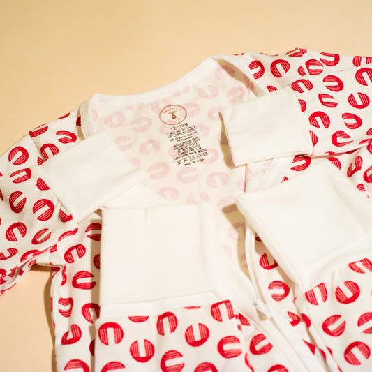 White romper with red pattern on sleeves against a beige background