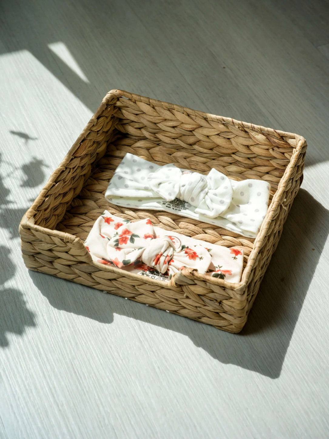 Woven basket with folded baby head wrap clothes on a light wooden floor