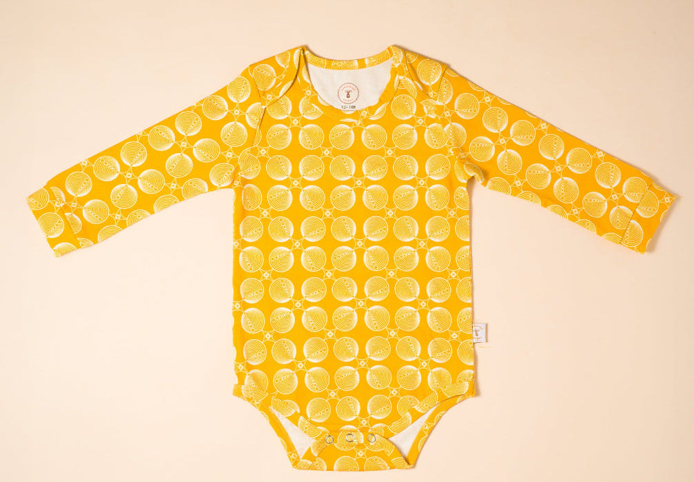 Yellow baby onesie, bodysuit  with a pattern on a beige background