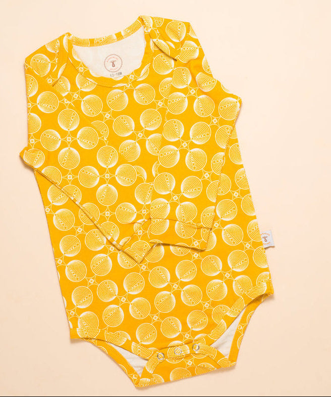 Yellow bubble-patterned baby romper,onesie, bodysuit  on a beige background