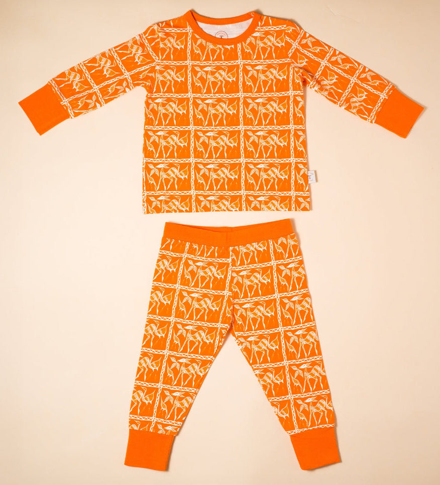 Orange organic cotton children's pajama set with white pattern on a beige background