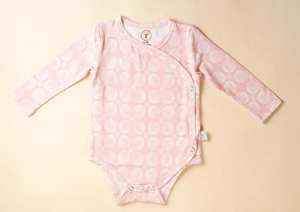 Pink baby onesie, bodysuit  with a pattern on a beige background