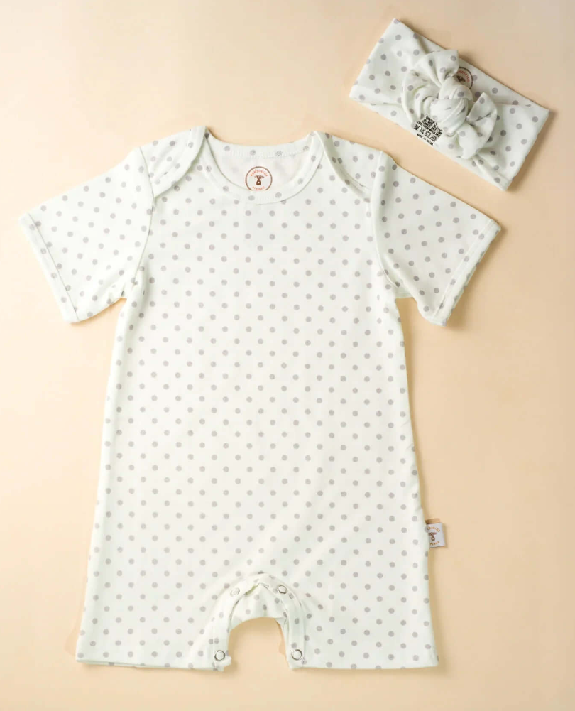 Baby romper with short sleeves and a matching headband on a beige background