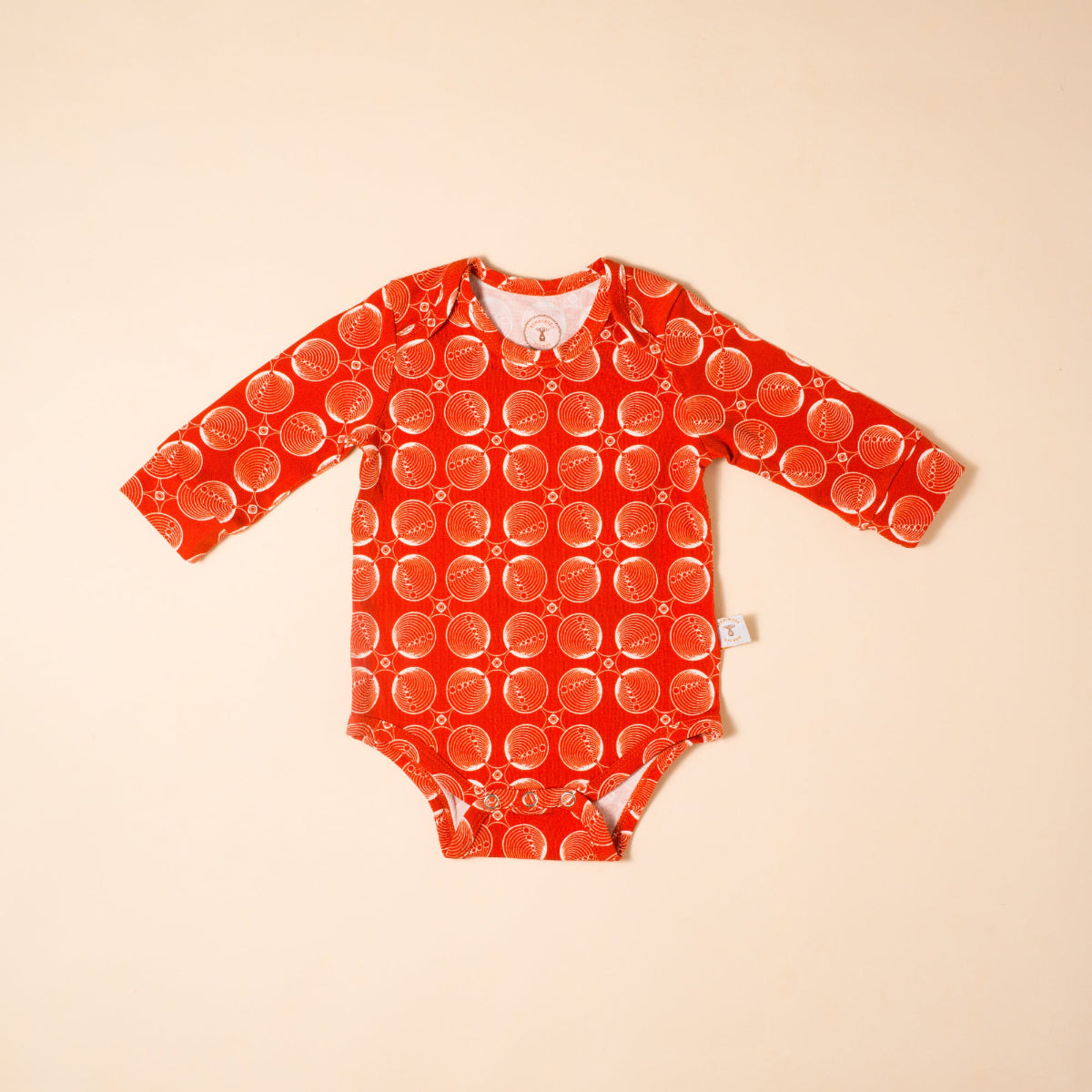 Red baby onesie, bodysuit with pattern on a beige background