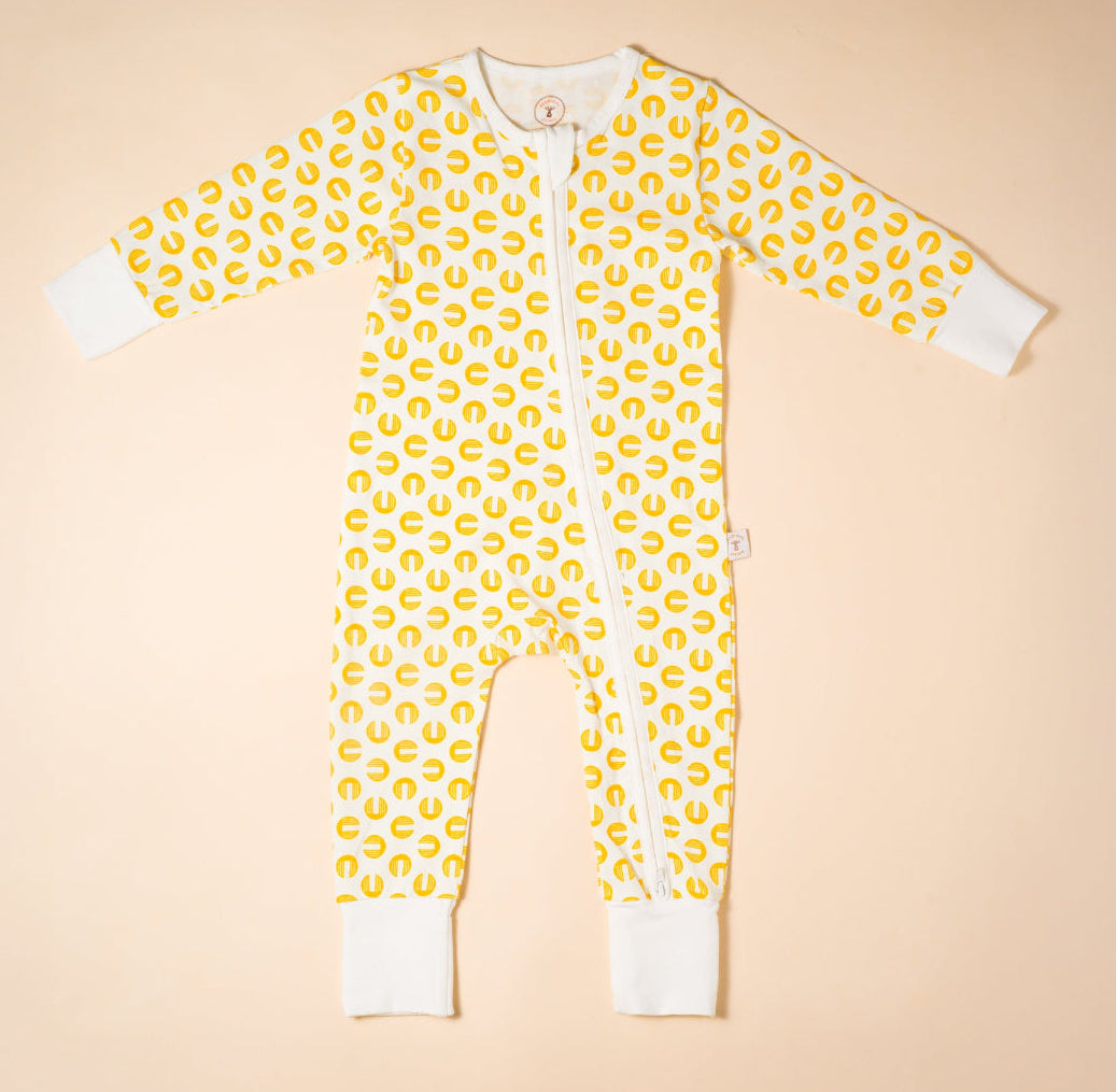 Yellow baby onesie , romper with white pattern on a beige background